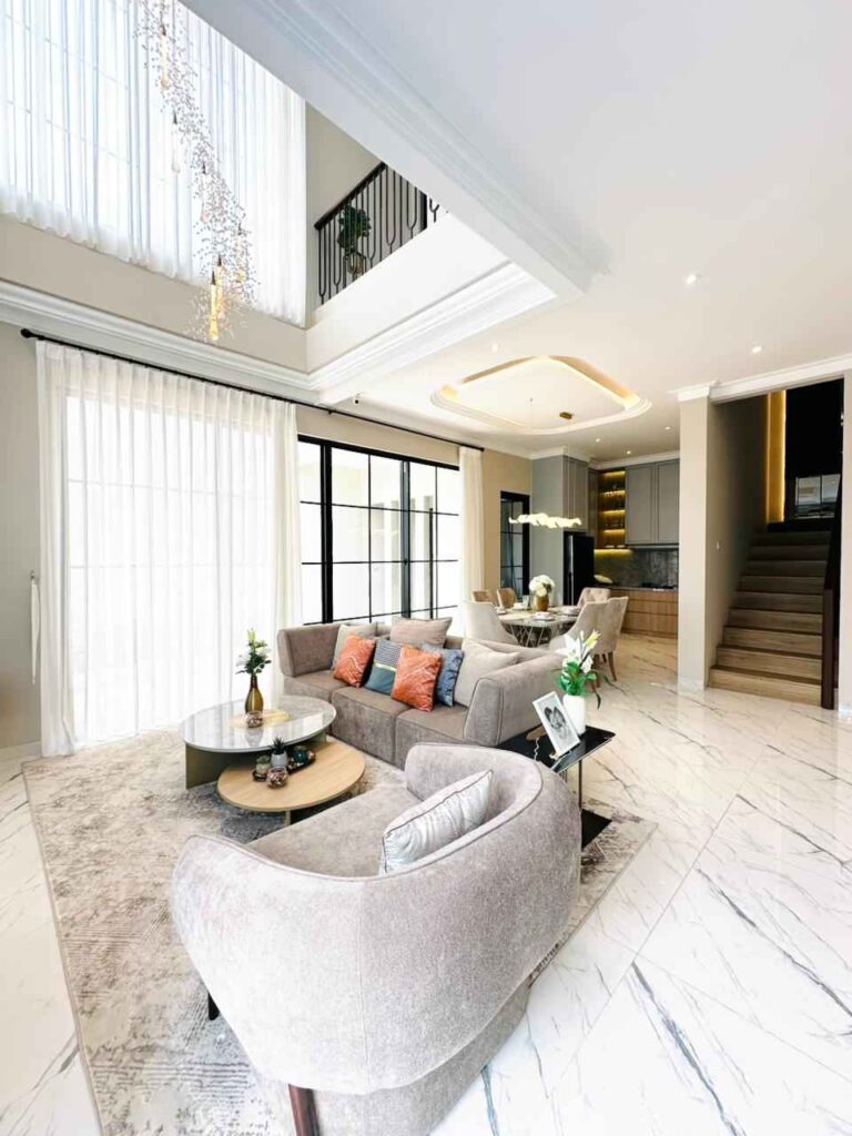 bright modern living room with a gray sectional colorful throw pillows and a circular coffee table on a light rug by large windows with sheer curtains   citragran cibubur | perumahan baru lokasi strategis cibubur