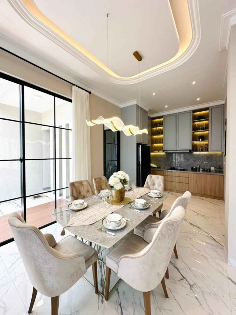 open concept dining area with a marble table six beige upholstered chairs and a sculptural pendant light above   citragran cibubur | perumahan baru lokasi strategis cibubur