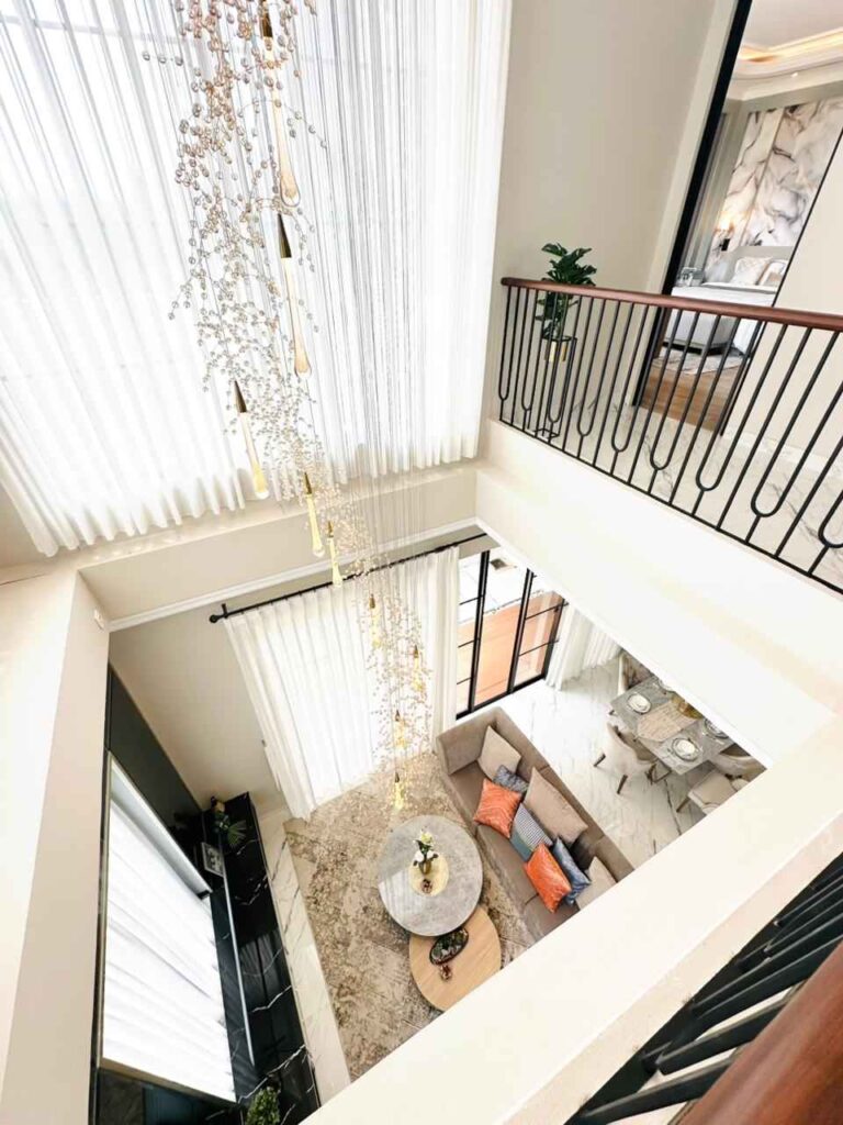 open two story living area seen from above with a hanging chandelier and sheer curtains overlooking a seating nook and dining area   citragran cibubur | perumahan baru lokasi strategis cibubur