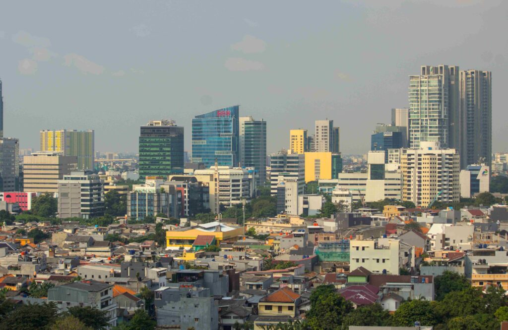 city skyline with tall glass office buildings in the background and a dense row of low rise houses in the foreground under a blue sky   citragran cibubur | perumahan baru lokasi strategis cibubur